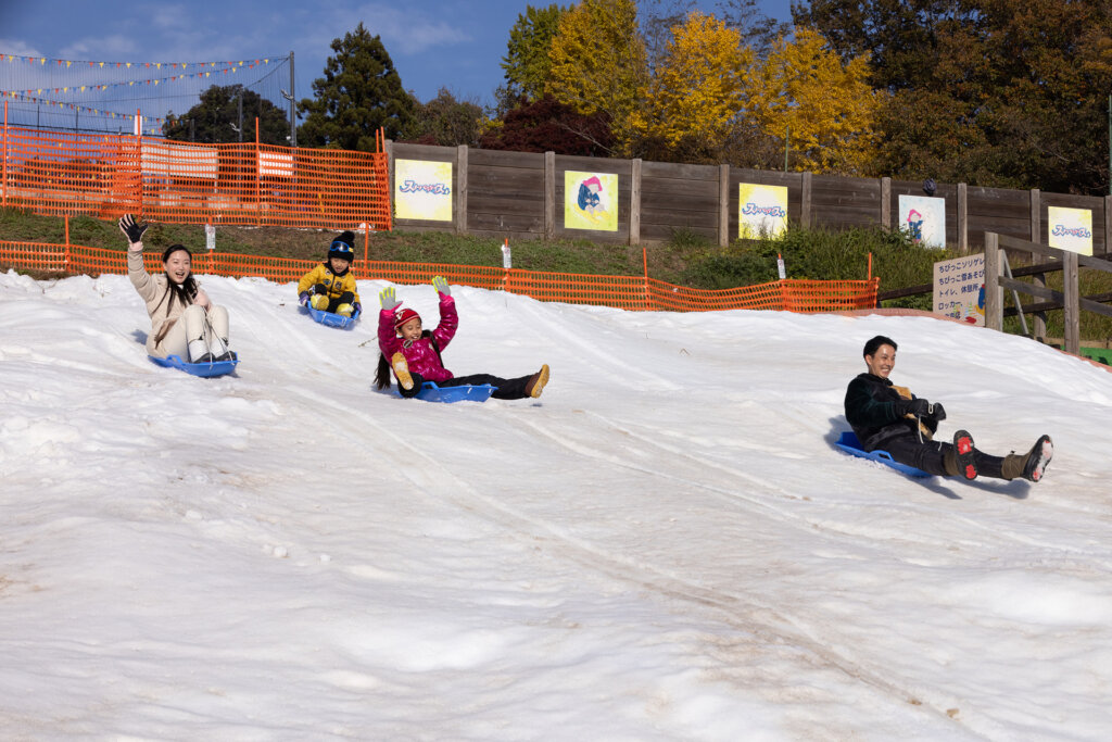 雪山で遊ぶ子ども　スライダーを滑る