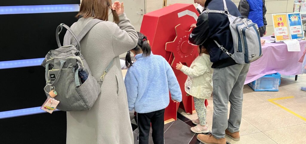 大型の回転抽選機に挑戦する親子