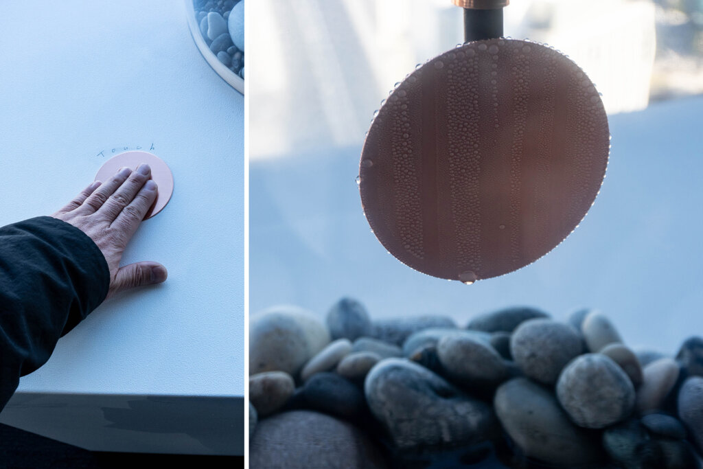 雫の垂れる銅板を手で触れる