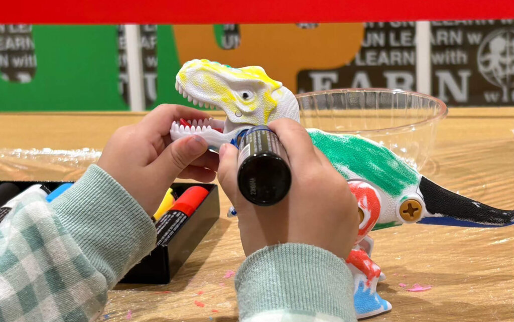 恐竜のオブジェに色を塗る子ども