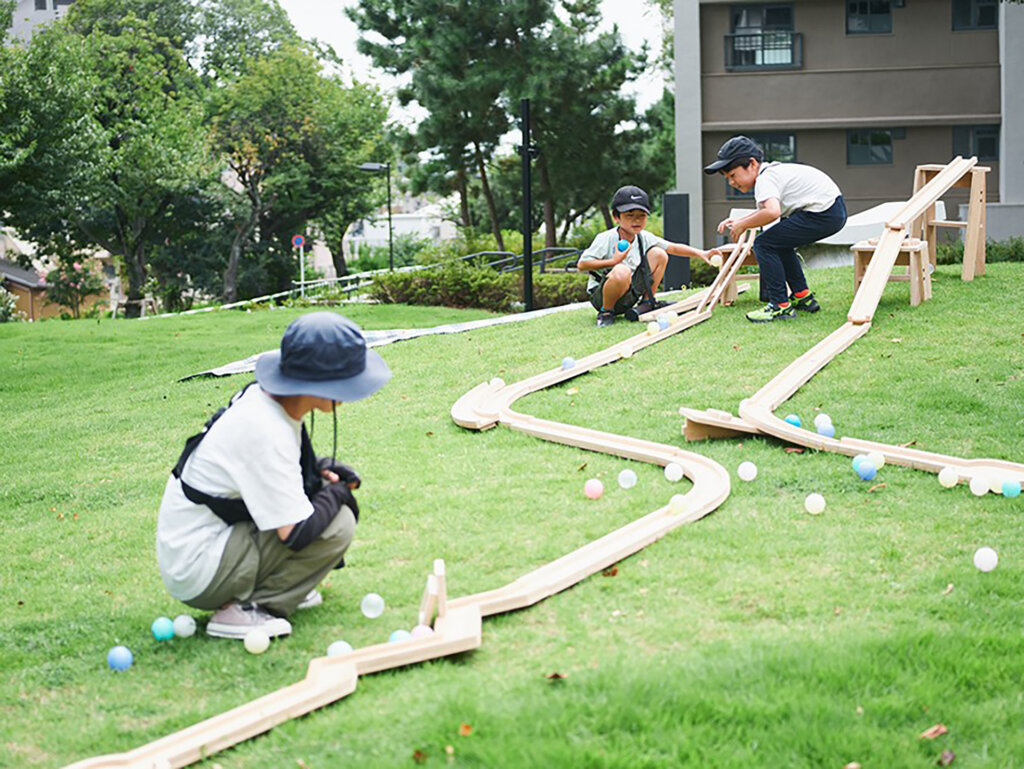 丘の上でボールを転がす子ども